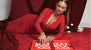 Elegante Frau in einem roten Kleid mit goldenem Schmuck, die entspannt auf rotem Samt liegt und Backgammon spielt. Die luxuriöse Atmosphäre und die warmen Farben sorgen für einen modernen und glamourösen Look