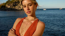 picture of a blond woman with a sea background and a gold necklace on her